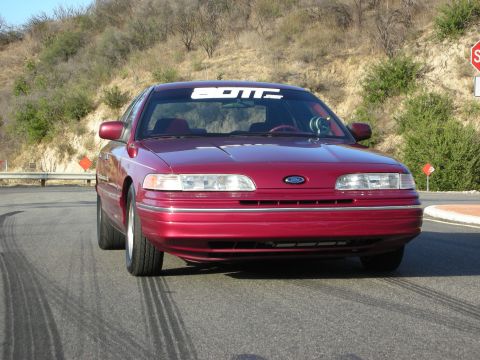 1992 Ford Crown Victoria - Front view of a red 1992 Ford Crown Victoria with a custom banner on the windshield.