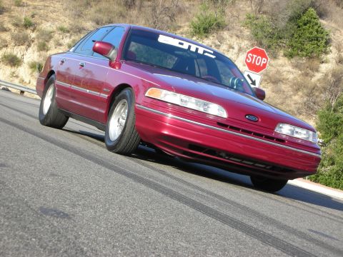 1992 Ford Crown Victoria - 1992 Ford Crown Victoria with "BOTZ" banner on windshield, seen on a road with tire marks.