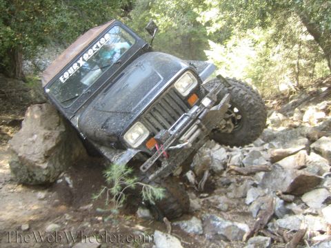 1987 Suzuki Samurai - A Jeep Wrangler navigates a challenging rocky trail, tilted significantly to one side.