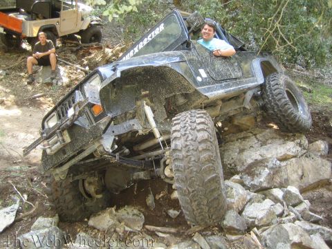 1987 Suzuki Samurai - An off-road vehicle navigates a rocky incline, with another vehicle and a person visible in the background.