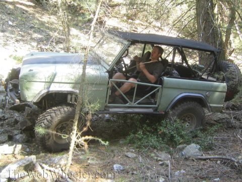 1987 Suzuki Samurai - Ford Bronco with custom roll cage and off-road tires is driven over rocks and through trees.