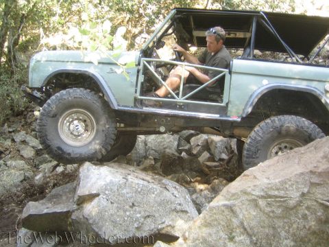 1987 Suzuki Samurai - Driver maneuvers an off-road vehicle over large rocks on a trail.