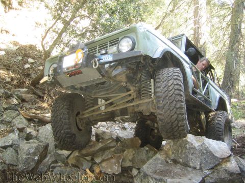 1987 Suzuki Samurai - A modified off-road vehicle tackles a challenging rocky terrain, its suspension and tire grip.