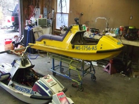 1995 Ford Mustang - A cluttered garage contains two jet skis, one yellow and one white, with various tools and supplies visible.