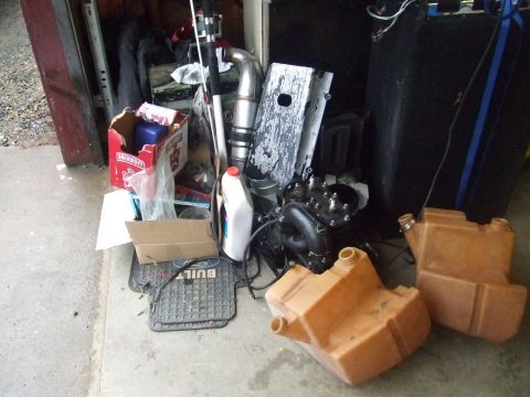 1995 Ford Mustang - Various engine parts and fuel tanks are stored in a cluttered garage environment.