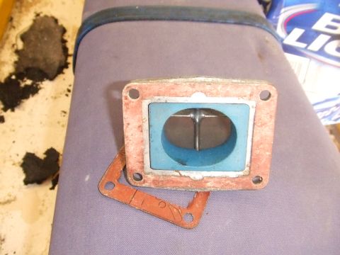 1995 Ford Mustang - A close-up view of a carburetor throttle body and its gasket, likely for an older vehicle.