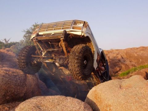 1986 Ford Bronco - This 1986 Ford Bronco is navigating a challenging rocky terrain, tilted at a precarious angle.