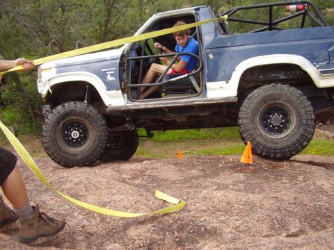 1986 Ford Bronco - A 1986 Ford Bronco is being pulled by a yellow strap while off-roading over rocks.