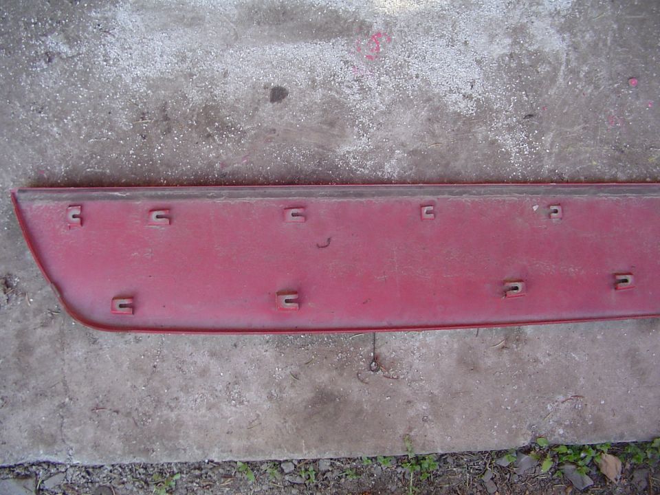 Red plastic car trim piece with multiple mounting clips on the back