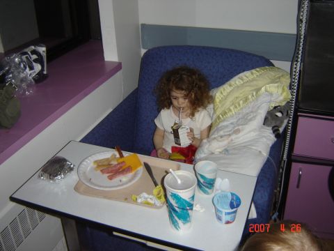 1993 Ford Bronco - A child sits in a hospital bed with a meal tray, drinking from a juice box.