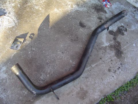 1994 Ford Probe - A black exhaust pipe is shown on a concrete surface, with a discarded can in the background.