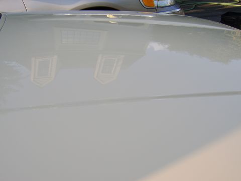 1996 Mercury Grand Marquis - Reflection of a house with dormer windows is visible on the polished surface of a car's hood.