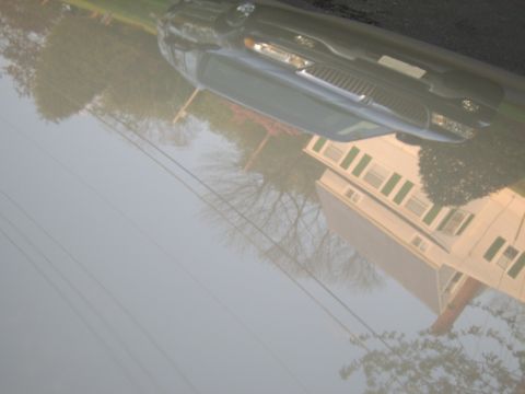 1996 Mercury Grand Marquis - A dark sedan is parked on a street in front of a house with green shutters.