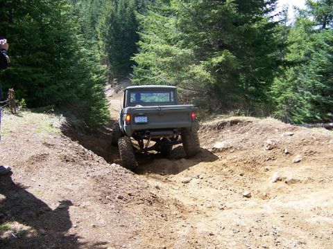 1968 Ford Bronco - 1968 Ford Bronco navigates a challenging off-road course, kicking up dirt.
