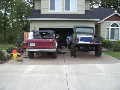 1968 Ford Bronco - Two pickup trucks are parked in a driveway, one red and one dark green.