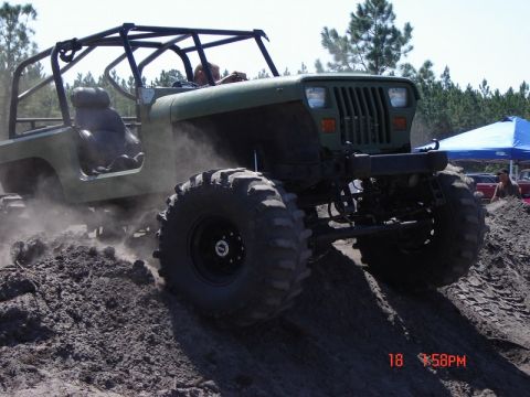 1989 Ford Bronco - This heavily modified off-road vehicle navigates a dirt mound, kicking up dust.