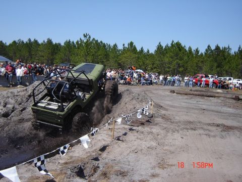 1989 Ford Bronco - Off-road vehicle navigates a challenging dirt course with spectators in the background.