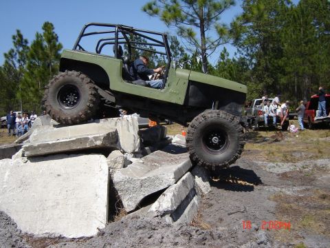 1989 Ford Bronco - A modified Jeep CJ-7 navigates an obstacle course with spectators in the background.