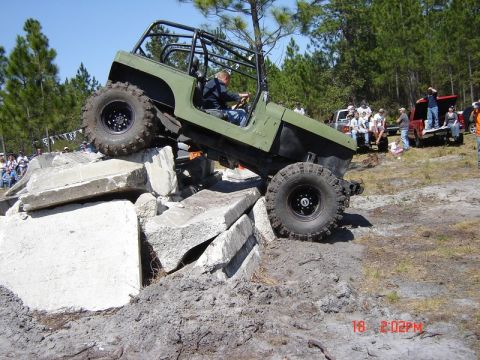 1989 Ford Bronco - Off-road Jeep navigates a challenging obstacle course with onlookers present.