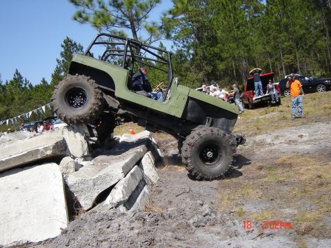 1989 Ford Bronco - A modified Jeep navigates a challenging obstacle course with spectators observing the event.