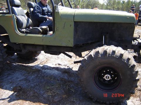 1989 Ford Bronco - This modified off-road vehicle is seen from the side with a driver inside.
