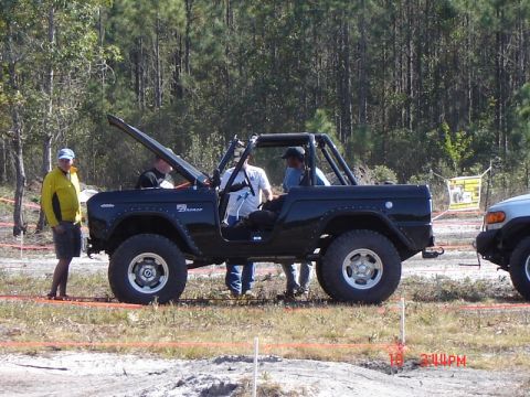 1989 Ford Bronco - A black 1989 Ford Bronco is seen with its hood open and a roll cage installed, parked outdoors.