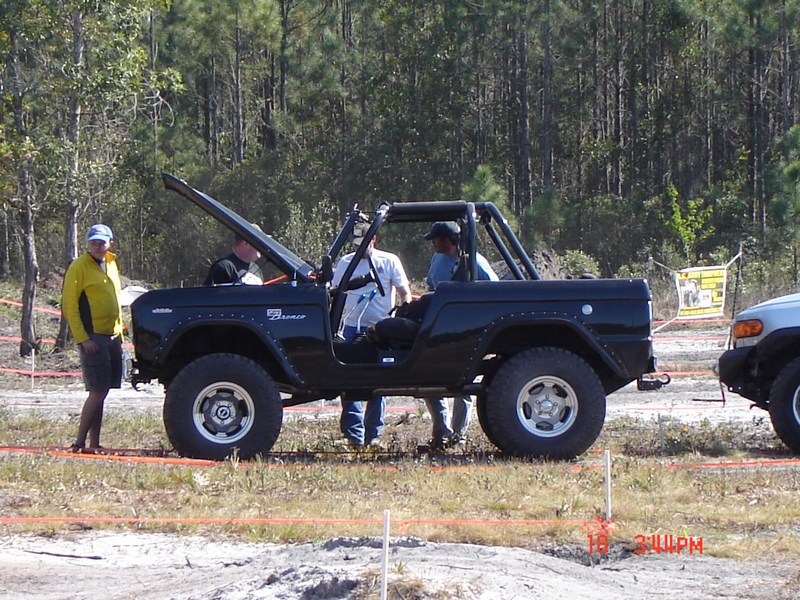 Black 1989 Ford Bronco side view with open hood and roll cage