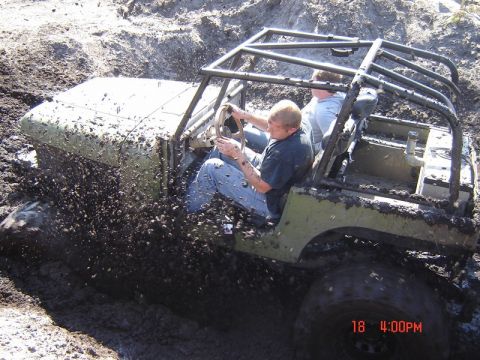 1989 Ford Bronco - Two people in an off-road vehicle struggle through deep mud.