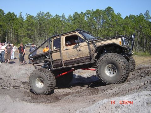 1989 Ford Bronco - This heavily modified truck is shown navigating a muddy terrain during an off-road event.