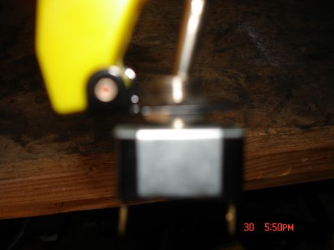 1979 Ford Bronco - A toggle switch is shown in detail, with a yellow lever and a black base against a wooden background.
