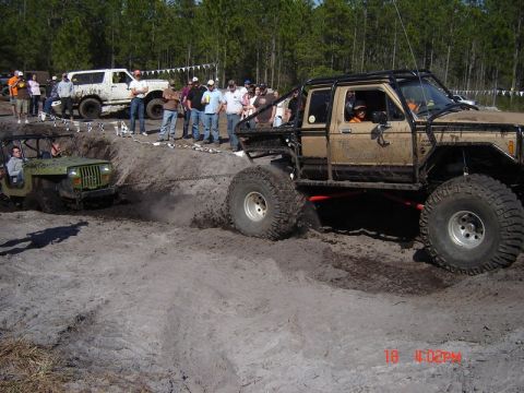 1989 Ford Bronco - Two off-road vehicles are engaged in a tug-of-war in a muddy terrain.