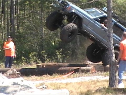 1989 Ford Bronco - An off-road SUV is captured mid-air as it jumps over a series of logs during an event.