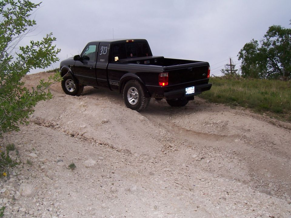 Black pickup truck with number 313 on the door driving on a dirt road