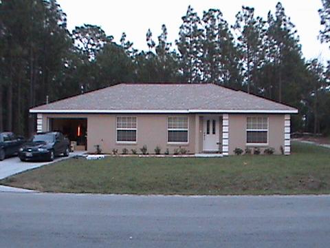 1986 Ford Bronco - A house with a tan exterior and a two-car garage, with two vehicles visible.