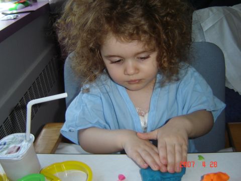 1993 Ford Bronco - A child is focused on playing with modeling clay, with a drink and toys on the table.