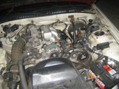 1991 Mazda RX-7 - Close-up view of the engine compartment of a vehicle, showing various mechanical components.