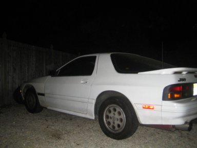 1991 Mazda RX-7 - A white 1991 Mazda RX-7 is parked outdoors at night, showing its rear quarter panel and spoiler.