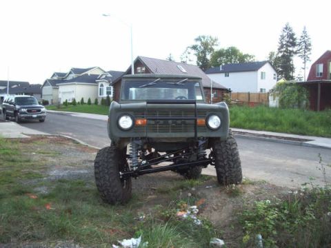 1968 Ford Bronco - A lifted 1968 Ford Bronco sits on a dirt embankment next to a suburban street.