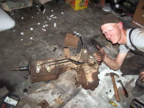 1968 Ford Bronco - Man with transmission assembly on floor, giving a thumbs up.