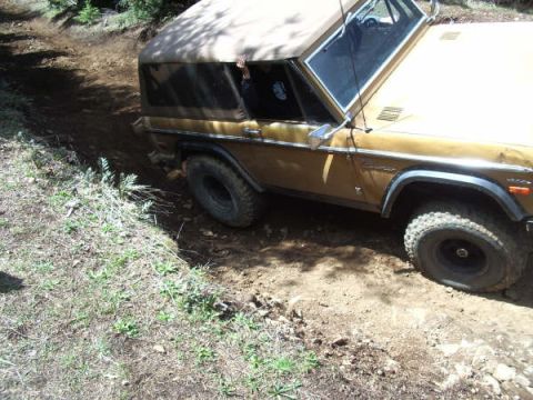 1968 Ford Bronco - A 1968 Ford Bronco navigates a rough dirt path, its tires kicking up dust.