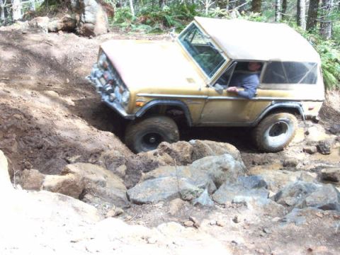 1968 Ford Bronco - This 1968 Ford Bronco is shown tackling a challenging off-road course with significant rock obstacles.