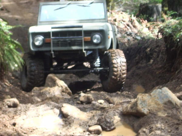 1968 Ford Bronco navigating a rocky, muddy trail