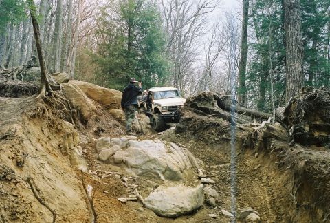 1978 Ford Bronco - 1978 Ford Bronco tackling a challenging off-road course in a wooded area.