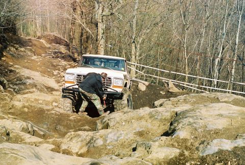 1978 Ford Bronco - A 1978 Ford Bronco tackles a challenging off-road course, with a person adjusting the winch.
