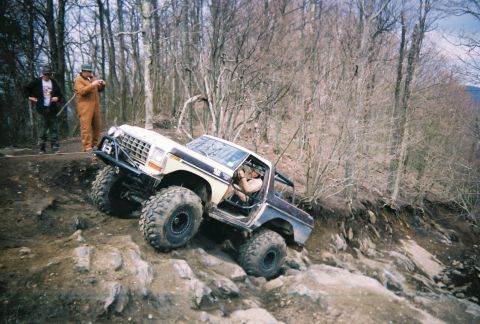 1978 Ford Bronco - This modified 1978 Ford Bronco is navigating a challenging off-road course in a wooded area.