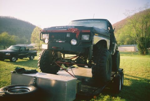 1978 Ford Bronco - A heavily modified black pickup truck, possibly a 1978 Ford Bronco, is shown on a trailer with a red grille and "ALASKAN EXTREME" text on t…