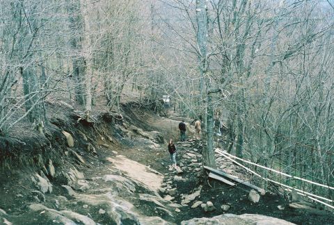 1978 Ford Bronco - People navigate a challenging, rocky trail through a bare forest.
