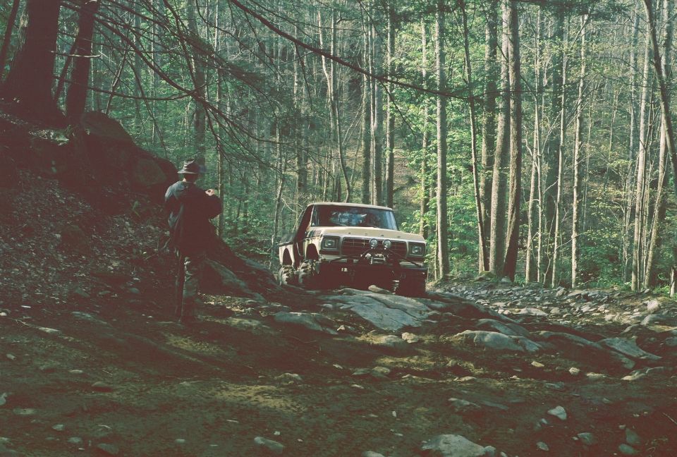 SUV driving on a dirt path through a forest