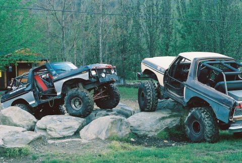 1978 Ford Bronco - Two off-road vehicles are seen navigating a rocky trail, with one vehicle appearing to climb over obstacles.