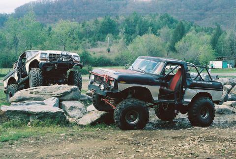 1978 Ford Bronco - A 1978 Ford Bronco is parked outdoors next to a trailer loaded with debris.